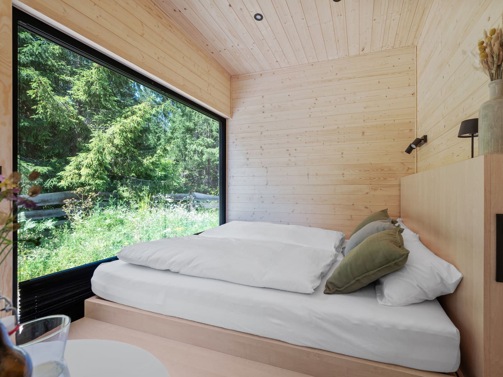 Bett am bodentiefen Fenster mit Blick in den Wald
