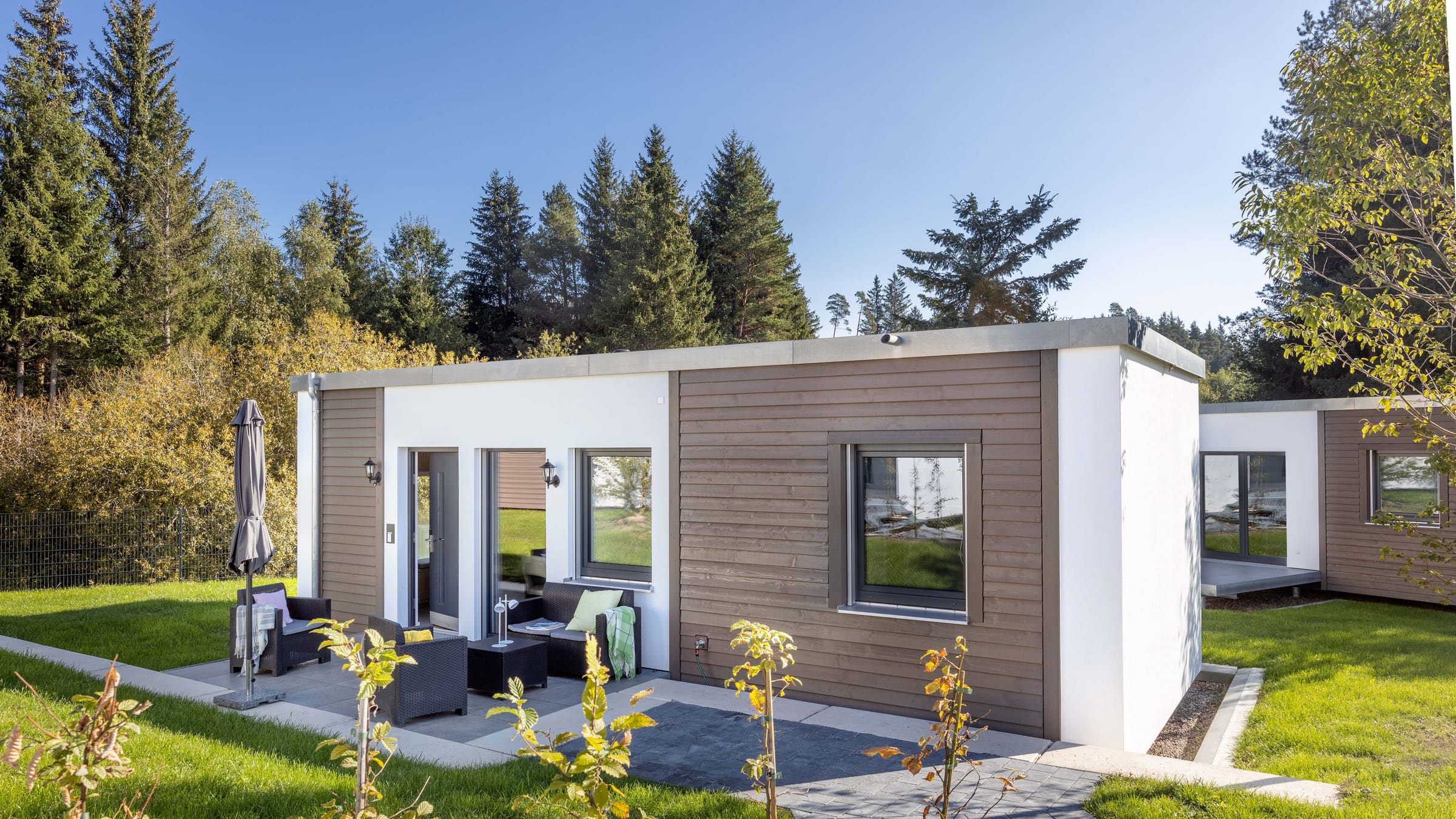 Bungalow with timber facade and terrace at the forest edge
